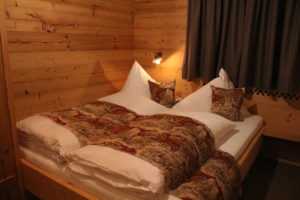 Das Schlafzimmer mit angrenzendem Badezimmer aus Altholz gezimmer mit rotkarierten Vorhängen und ganz besonders gemütlicher Atmosphäre